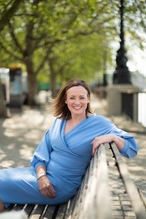 Photograph of Sally Anderson executive leadership coach sat on a bench by the River Thames in London